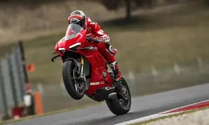 Czerwona Ducati Panigale V4R na torze, z przednim kołem w powietrzu. Kierowca w kombinezonie Ducati Corse.
