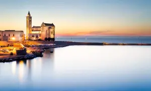 Tramonto sul porto di Trani, con la cattedrale illuminata che domina il paesaggio. Un'incantevole vista dei dintorni di Trani.