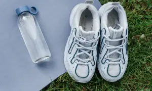 Para pozbyć się smrodu z butów, potrzebujesz świeżego powietrza i słońca. Buty sportowe i butelka wody na macie do ćwiczeń.