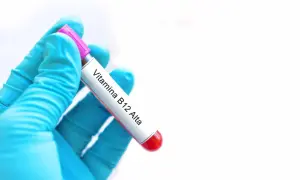 Guanto blu tiene provetta con etichetta "Vitamina B12 Alta". Risultato di analisi del sangue.