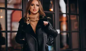 Kobieta w czarnej, futrzanej kurtce skórzanej i beżowym golfie. Dowiedz się, jak zmiękczyć skórzaną kurtkę, by wyglądała jak nowa.