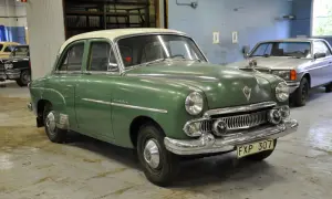 Grön Vauxhall Velox med vitt tak står i ett garage. En silverfärgad bil syns i bakgrunden.