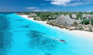 Idealny dzień, kiedy na Zanzibar. Turkusowa woda, biała plaża i łódź z turystami.