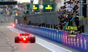 Un coche de Fórmula 1 cruza la meta, con el equipo celebrando la victoria de Lewis Hamilton en el gran premio.