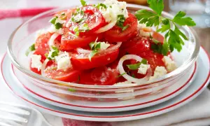Frischer tomatensalat mit feta, Zwiebeln und Petersilie, garniert mit Pfeffer und Salz. Ein leichter Genuss.