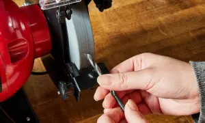 Persona afila brocas en una amoladora.