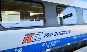 Boczna ściana pociągu PKP Intercity z logo IC. Widoczne okna, w których odbija się niebo i peron. To właśnie eic co to za pociąg!