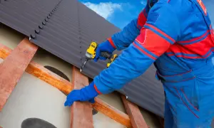 Handwerker verlegt mit Akkuschrauber Bitumenwellplatten auf einem Dach.