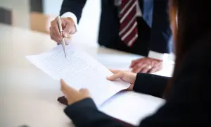 Prawnik wskazuje piórem na dokument, omawiając, czy apelacja jest płatna.