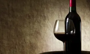 Butelka i kieliszek z czerwonym winem na tle. Czy czerwone wino się chłodzi?