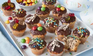 Bunte Muffins mit Schokoglasur und Gummibärchen, perfekt für einen Kindergeburtstag.