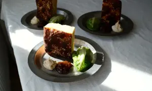 Enkel lyxig middag: bitar av rostat bröd med sesamfrön, serverade med sallad, en klick krämig röra och sylt på metalltallrikar.