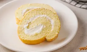 Zwei Scheiben einer saftigen Zitronenrolle mit cremiger Füllung auf einem Teller. Ein einfaches Zitronenrolle Rezept zum Nachbacken.