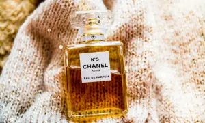 Elegancka butelka Chanel N°5 Eau de Parfum na miękkim, błyszczącym swetrze.