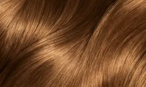 Capelli castani con riflessi dorati che ricordano i colpi di sole caramello, mossi e luminosi.