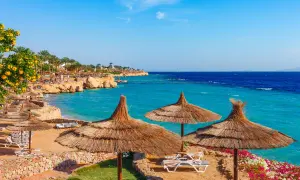 Słoneczna plaża w Sharm el Sheikh, z turkusowym morzem i leżakami pod strzechą. Idealne miejsce na wakacje, gdzie wiza otwiera drzwi do raju.