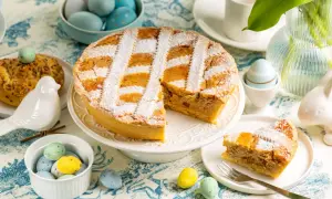 Une délicieuse pastiera napoletana saupoudrée de sucre glace, entourée d'œufs de Pâques colorés et d'une décoration printanière.
