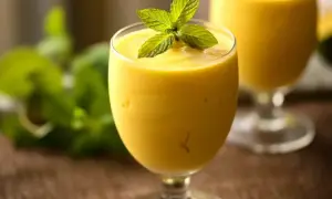 Orzeźwiający mango lassi, oryginalny przepis. Kremowy napój z mango i jogurtu, ozdobiony listkami mięty. Idealny na upalne dni.