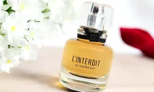 Elegancki flakon perfum L'Interdit Givenchy, otoczony białymi kwiatami i czerwoną szpilką, symbolizuje odwagę i wyrafinowanie.