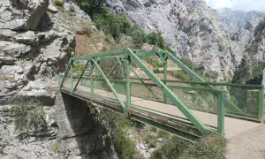 Puente Dobra, una estructura verde metálica cruza un desfiladero rocoso con vegetación.