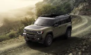 Jeep Recon in verde militare affronta un sentiero sterrato in montagna, pronto per ogni avventura.