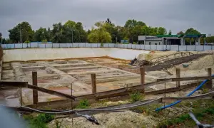 Widoczne **objawy zniszczenia fundamentu pomnika** na co patrzeć przy odbiorze: pęknięcia, wykwity, wilgoć. Teren budowy z betonowymi elementami.