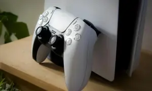 Biały kontroler DualSense leży obok konsoli PlayStation 5. To idealny moment na podsumowanie roku z grami, czyli playstation wrap up.