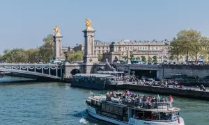 Rejs po Sekwanie w Paryżu. Statek wycieczkowy z turystami podziwia most Aleksandra III i zabytkowe budynki.