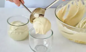 Eine Portion cremiger Pistazienmousse wird mit einem Löffel in ein Glas gegeben.