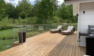 En nybyggd altan med trall som väntar på att måla. Solstolar och grill står redo för sommaren.
