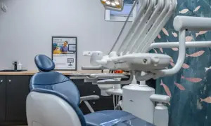 Nowoczesny gabinet stomatologiczny, gotowy na sanację zębów. Wygodny fotel, lampa i estetyczna tapeta tworzą przyjazną atmosferę.