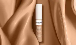 Un correcteur jaune L'Oréal True Match, présenté sur un fond satiné couleur peau.