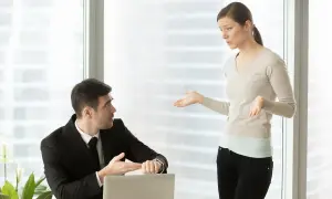 Mężczyzna w garniturze pokazuje na zegarek, kobieta gestykuluje. Dyskutują o wezwaniu do sądu a praca.