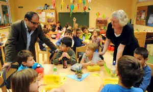 Lehrer und Kinder bei einem gallery walk im Klassenzimmer. Ein Junge hebt die Hand.