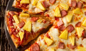 Pyszna pizza z ananasem i szynką, z ciągnącym się serem i chrupiącym ciastem. Idealna na szybki obiad.
