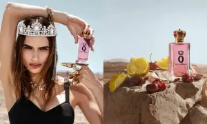 Królowa w koronie i biżuterii trzyma flakon perfum Dolce & Gabbana Q. Obok, na kamieniu, leżą wiśnie i cytryny.