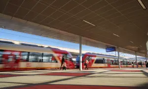 Pasażerowie kupują skm bilety warszawa na peronie, gdzie pociągi SKM w Warszawie szybko przejeżdżają.