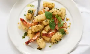 Gnocchi mit Garnelen, verfeinert mit Kräutern und Öl, auf einem weißen Teller angerichtet.