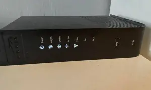 Czarny router Arris TG2492 z widocznym przyciskiem WPS i wskaźnikami statusu: Power, US/DS, Online, 2.4 GHz, 5 GHz, Tel 1, Tel 2.