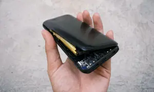 Dłoń trzyma powerbank z widoczną, spuchniętą baterią. Widać elektronikę i złącza.