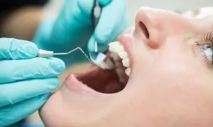 Dentysta bada zęby pacjentki, oceniając przeciwwskazania do lakierowania.