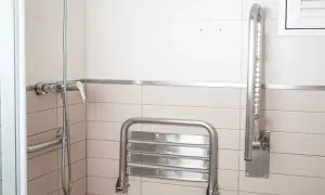 Doccia con maniglione di sostegno verticale e sedile ribaltabile. La posizione del maniglione doccia è strategica per la sicurezza.