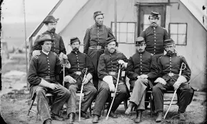 Gruppbild av nio män i uniformer från amerikanska inbördeskriget. De sitter och står framför ett tält. En enhetlig serie av militärkläder.