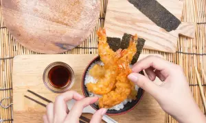 Ręce układają chrupiące krewetki w tempurze na ryżu. Idealny przepis na tempurę, by poczuć smak Japonii.
