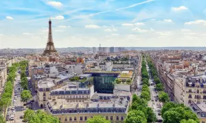 Vy över Paris med Eiffeltornet i fjärran. En grönskande allé leder mot stadens centrum, där takåsarna vittnar om stadens rika historia och många museum.