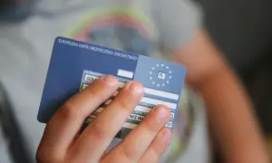 Dziecko trzyma Europejską Kartę Ubezpieczenia Zdrowotnego, niezbędną do podróży, np. na Słowację.