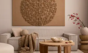 Przytulny salon z beżową kanapą, grubym pledem i misą z dyniami. Na ścianie wisi imponujące dzieło sztuki – obrazy strukturalne w kształcie serca.