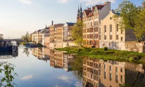 Nad Odrą w Opolu, zabytkowe kamienice odbijają się w spokojnej wodzie. To piękne opole atrakcje, które warto zobaczyć.