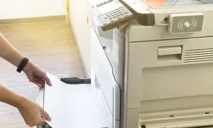 Mani inseriscono un foglio di carta in una stampante, pronta per stampare in formato super A3.