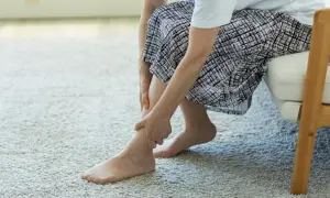 Kobieta masuje bolącą łydkę. Czy Diclovit na co pomoże złagodzić ból?